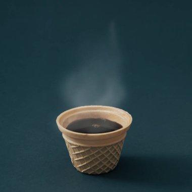 Siyah arka planda waffle külahında sıcak kahvenin yakın görüntüsü. Minimum kahve estetiği konsepti. Yaratıcı dondurma kahve fikri.