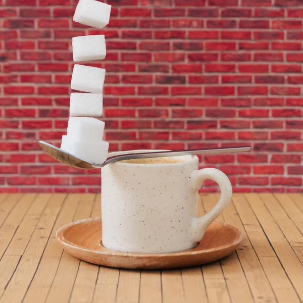 由咖啡 勺子和飞糖方块制成的创意构图 与红砖墙背景图相映衬 最小食物和饮料的概念 迷人的咖啡和糖立方体布局 咖啡美学观念 — 图库照片