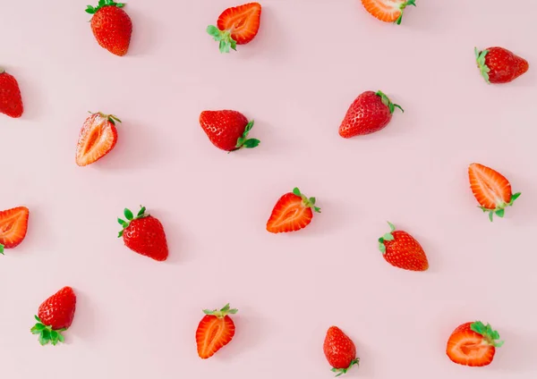 Trendy fruit pattern made of fresh and healthy strawberries on light pastel pink background. Creative minimal strawberry pattern composition. Nature food concept. Fancy pink background flat lay.