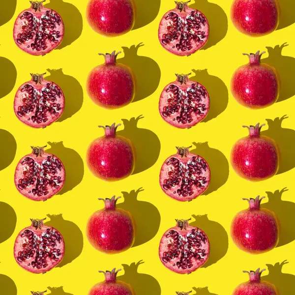 Trendy fruit pattern made of fresh red pomegranates on light yellow background. Minimal healthy food layout. Nature fruit concept. Pomegranate aesthetic background pattern.