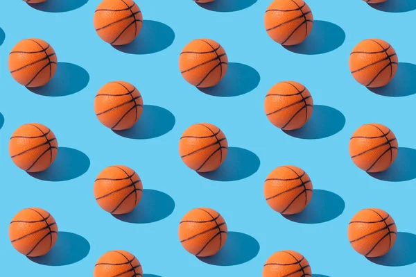 Trendy basketball pattern composition on light blue background. Minimal sport concept. Creative orange ball arrangement. Basketball aesthetic background.