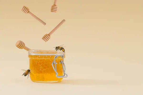Creative layout made with honey dippers falling into jar full of natural honey and honeycombs and honey bees flying around on light cream background. Minimal nature concept. Trendy healthy food idea.