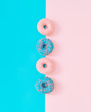 Açık mavi ve pastel pembe arka planda pembe ve mavi jöleli çörekler. Yaratıcı bir kavram. En az lezzetli yemek fikri. Lezzetli donut kompozisyonu. Estetik çörekler.