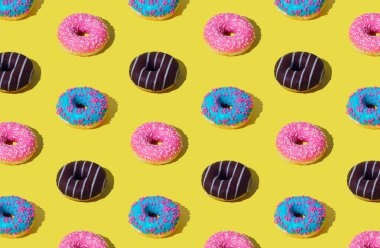 Açık sarı arka planda renkli donutların yaratıcı deseni. Minimum konsept. Moda donut modeli arka plan. Lezzetli yemek kompozisyonu. Estetik çörekler.