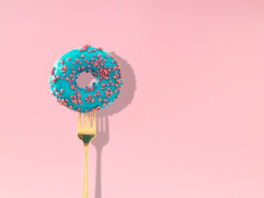 Pastel pembe arka planda çatala batırılmış lezzetli mavi jöleli donut. Yaratıcı sanat. Çağdaş tarz. Fotokopi alanı olan en az yiyecek konsepti. Donut estetik arka planı.