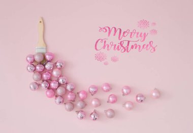 Pastel pembe arka planda pembe Noel mücevherleriyle boya fırçasından yapılmış yaratıcı modayı. Asgari Noel veya Yeni Yıl dekorasyonu konsepti. Kış tatili kutlama fikri. Düz yatıyordu.