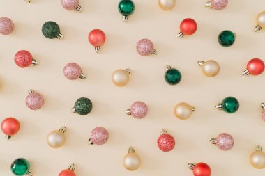 Pastel krem arka planında yaratıcı renkli Noel süsleri deseni. Asgari Noel ya da yeni yıl konsepti. Modaya uygun bir tatil partisi fikri. Düz yatıyordu, manzaranın tepesinde..
