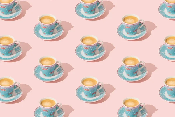 Trendy pattern made of blue cup of coffee on light pastel peachy pink background. Minimal concept. Creative coffee pattern idea. Fancy peachy pink background. Coffee aesthetic.