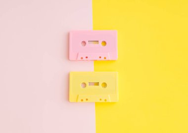Pastel pembe ve sarı arkaplandaki retro pembe ve sarı ses kasetlerinin düzeni. Retro teknolojinin yaratıcı konsepti. 80 'ler estetik. Klasik ses kasedi fikri. Geçmişe özlem.