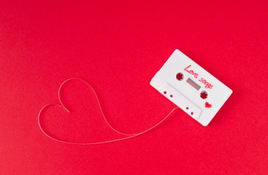 Kırmızıda kalbi şekillendiren gevşek bantlı ses kaseti. Asgari aşk konsepti. Yaratıcı retro teknoloji aşk kartı. 80 'ler estetik. Klasik kaset kaset aşk şarkıları fikri. Geçmişe özlem.