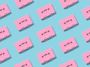 Açık mavi arka planda eski pembe ses kasetleriyle yapılmış bir model. Retro teknolojinin yaratıcı konsepti. 80 'ler estetik. Klasik ses kaset kalıbı fikri. Geçmişe özlem. Düz yatıyordu.