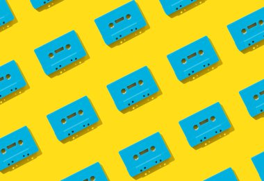 Sarı arkaplandaki retro mavi ses kasetlerinden yapılmış bir kalıp. Retro teknolojinin yaratıcı konsepti. 80 'ler estetik. Klasik ses kaset kalıbı fikri. Geçmişe özlem. Düz yatıyordu.