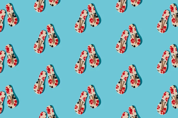 Creative sunlight summer pattern composition made with floral slippers on bright blue background. Minimal summer concept. Trendy summer vacation idea.