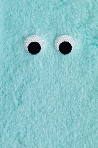 Cute fluffy monster made with light blue faux fur. Minimal concept. Creative funny face composition. An original blue fur cute fluffy monster background image idea. Flat lay, top of view.