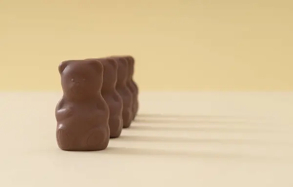 Pastel krem arka planda çikolatalı oyuncak ayılarla yapılan yaratıcı bir düzenleme. Yaratıcı tatlı yemek konsepti. Lezzetli çikolatalı oyuncak ayı fikri. Asgari düzeyde. Çikolata estetiği. Boşluğu kopyala.