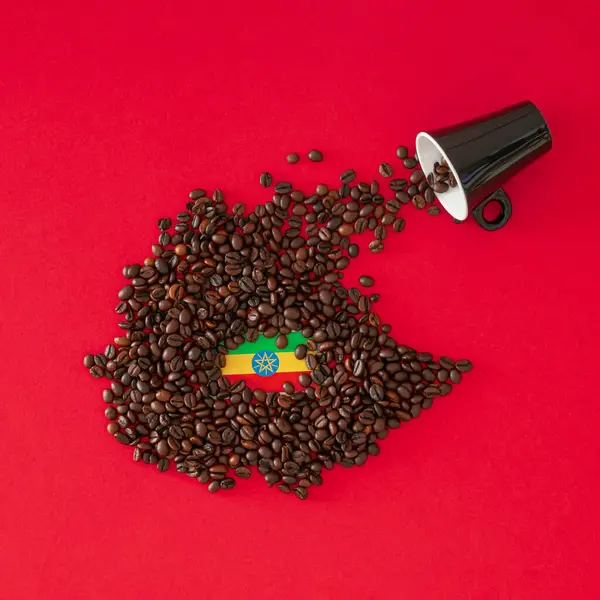Creative composition made with coffee cup, map of Ethiopia made with roasted coffee beans and Ethiopian flag on red background. Minimal layout. Ethiopia, the home of coffee concept. Flat lay.