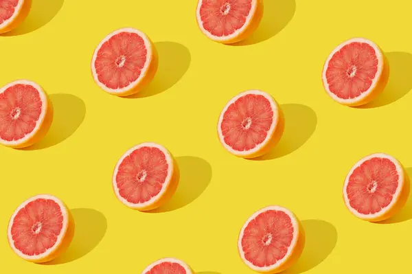 Trendy sunlight fruit pattern made with red grapefruit slice on yellow background. Minimal summer concept. Creative food idea. Grapefruit aesthetic.
