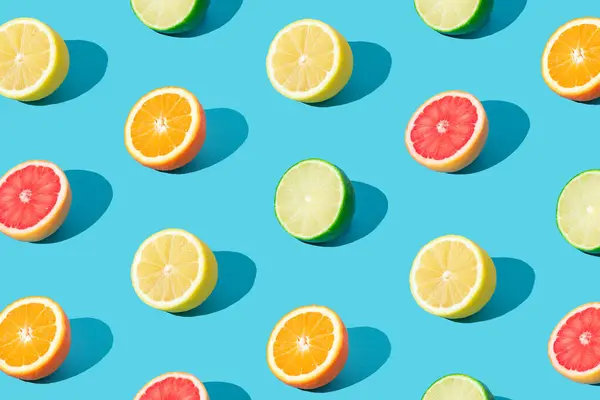 Colorful sunlight fruit pattern made of red grapefruit, orange, lime and lemon slices on light blue background. Minimal summer concept. Creative food idea. Citrus fruits aesthetic. Trendy colors idea.