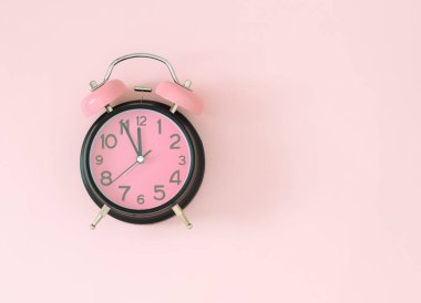 Pastel pembe ve siyah alarm saati açık renkli, pembe arka plan ve fotokopi alanı. Asgari zaman kavramı. Düz yatıyordu.