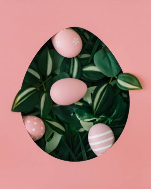 Spring composition with pink colored Easter eggs and green leaves visible through an egg shaped gap on pink background. Minimal Easter concept. Creative holiday layout. Easter aesthetic. Flat lay. clipart