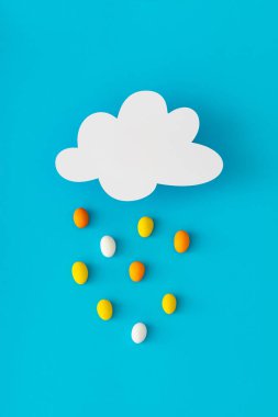 Creative composition made of cloud shape paper card note and colorful Easter eggs rain on blue background. Minimal Easter concept. Festive holiday layout. Easter aesthetic. Flat lay style. Top view. clipart