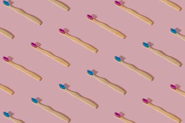 Pastel pembe arka planda organik bambu diş fırçası deseni bileşimi. Moda dişçi konsepti. Yaratıcı çevre dostu, geri dönüşümlü ve doğal ahşap diş fırçası desenli arka plan fikri.