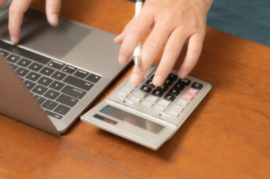 Meşgul işadamı işini becerikli bir şekilde dizüstü bilgisayarını, cep telefonunu ve hesap makinesini kullanarak yönetir, görevler ve hesap makineleri arasında sorunsuzca geçiş yapar,