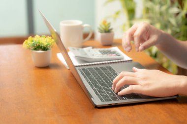 Meşgul işadamı işini becerikli bir şekilde dizüstü bilgisayarını, cep telefonunu ve hesap makinesini kullanarak yönetir, görevler ve hesap makineleri arasında sorunsuzca geçiş yapar,