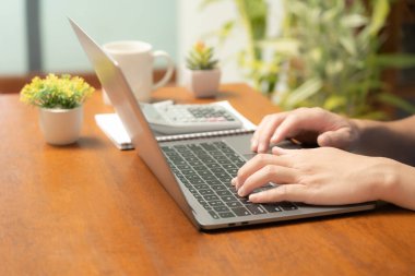 Meşgul işadamı işini becerikli bir şekilde dizüstü bilgisayarını, cep telefonunu ve hesap makinesini kullanarak yönetir, görevler ve hesap makineleri arasında sorunsuzca geçiş yapar,