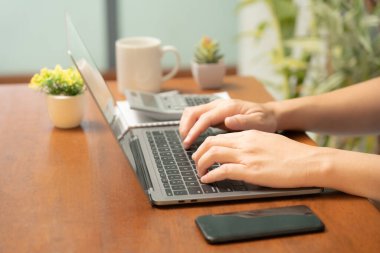 Meşgul işadamı işini becerikli bir şekilde dizüstü bilgisayarını, cep telefonunu ve hesap makinesini kullanarak yönetir, görevler ve hesap makineleri arasında sorunsuzca geçiş yapar,