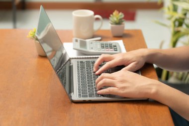 Meşgul işadamı işini becerikli bir şekilde dizüstü bilgisayarını, cep telefonunu ve hesap makinesini kullanarak yönetir, görevler ve hesap makineleri arasında sorunsuzca geçiş yapar,