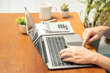 Meşgul işadamı işini becerikli bir şekilde dizüstü bilgisayarını, cep telefonunu ve hesap makinesini kullanarak yönetir, görevler ve hesap makineleri arasında sorunsuzca geçiş yapar,