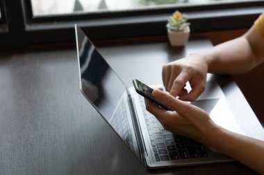 Bir insanın eli hem cep telefonunu hem de defterini ustalıkla manipüle ederek online alışveriş dünyasına girdi. Odaklanmış dikkatle, parmakları mobil cihazın canlı arayüzünde kaydırılmış.,
