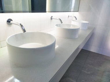 Geniş banyoda birden fazla kullanıcı için kolaylık ve işlevsellik sağlayan birkaç lavabo bulunuyor. Her lavabo zarif bir şekilde zarif musluklar ve parlak krom kaplamalarla tasarlandı. .