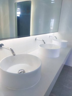 Geniş banyoda birden fazla kullanıcı için kolaylık ve işlevsellik sağlayan birkaç lavabo bulunuyor. Her lavabo zarif bir şekilde zarif musluklar ve parlak krom kaplamalarla tasarlandı. .