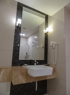 Banyo, sükunet cenneti, el değmemiş kiremitleri ve yumuşak ortam aydınlatmasıyla beni kucakladı. Işıl ışıl eşyalar ve tertemiz porselen lavabo beni ferahlatıcı bir zevke davet etti. 