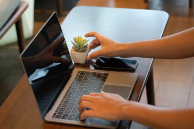 Bir insanın eli hem cep telefonunu hem de defterini ustalıkla manipüle ederek online alışveriş dünyasına girdi. Odaklanmış dikkatle, parmakları mobil cihazın canlı arayüzünde kaydırılmış.,