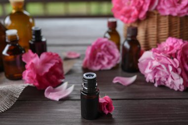 Ahşap masanın üzerinde aroma yağı olan kompozisyon, yakın plan. Ahşap masada gül aromalı bir şişe. Çiçek yağı. Bitkisel ilaçlar. Yan görünüm, seçici odak.