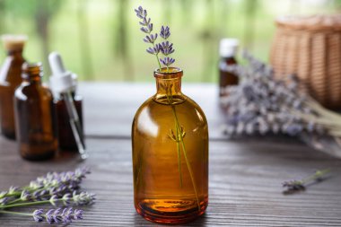 Masanın üzerinde doğal lavanta çiçekleri yağı bulunan şişeler. Şişedeki lavanta yağı. Çiçek yağı. Bitkisel ilaçlar. Yan görünüm.
