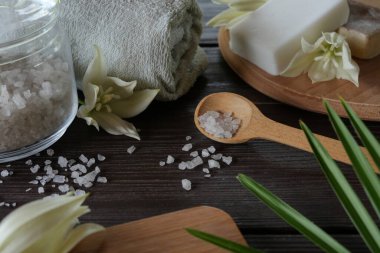 Deniz tuzu, doğal el yapımı sabun, doğal kozmetik yağ ve kırsal ahşap arka planda açelya çiçekleri olan renkli havlular. Sağlıklı cilt, vücut bakımı. SPA ve sauna konsepti. Yan görünüm.