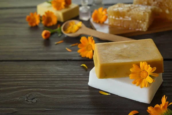 Natural handmade soap bars with calendula on rustic wooden background. Natural soap bars with essential oils and medicinal plants extracts. SPA concept. Side view, copy space for text.