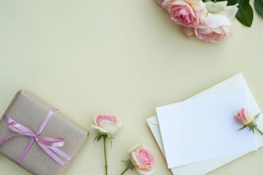 Boş düğün davetiyesi kâğıdı. Üzerinde gül ve hediye kutusuyla bej arka planda zarf var. Kadınsı blog. Tatil, tebrikler, anneler günün kutlu olsun. Uluslararası Kadınlar Günü.