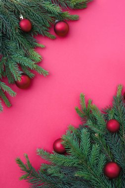 Noel kompozisyonu. Kırmızı arka planda süslemeleri olan kozalaklı ağaç dalları. Noel, kış, yeni yıl konsepti. Düz konum, üst görünüm, kopyalama alanı. Kış tatili kompozisyonu. 