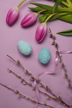 Easter holiday greeting, tilips, eggs, pussy willow. Spring season on pastel color. Top view, flat lay. Space fot text.