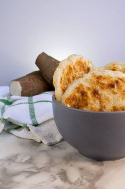 Arepas de yuca y queso tradicionales ecuatorianas junto a dos trozos de yuca cruda fresca