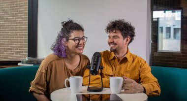 Mutlu Latin Amerikalı çift podcast talk show 'da sohbet ediyor, stüdyoda ses ekipmanlarıyla canlı kayıt yapıyorlar. Kadın ve erkek enerji dolu, canlı yayında tartışıyorlar. 