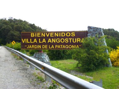 wooden sign with name of Villa La Angostura on roadside with railing clipart