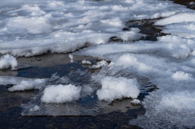 Altında çakıl taşları olan dağ nehri buzla kaplı.