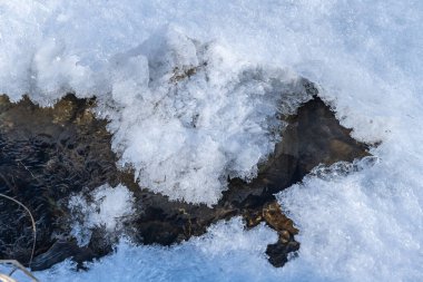 Altında çakıl taşları olan dağ nehri buzla kaplı.