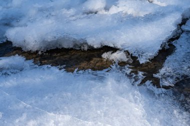 Altında çakıl taşları olan dağ nehri buzla kaplı.